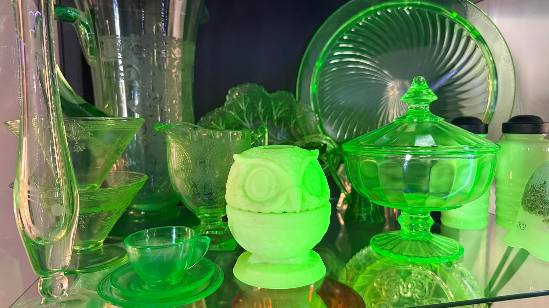 A collection of vintage uranium glass glowing green under UV light